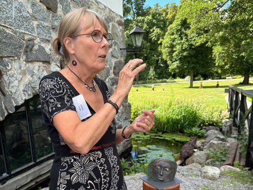 Kvinna pratar i en trädgård med skulpturer