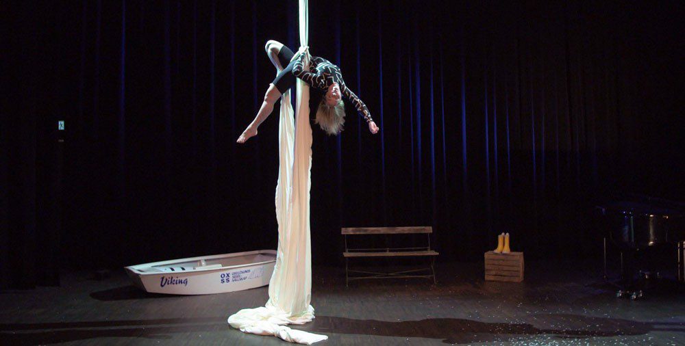 En kvinna hänger i tyger från taket på en scen