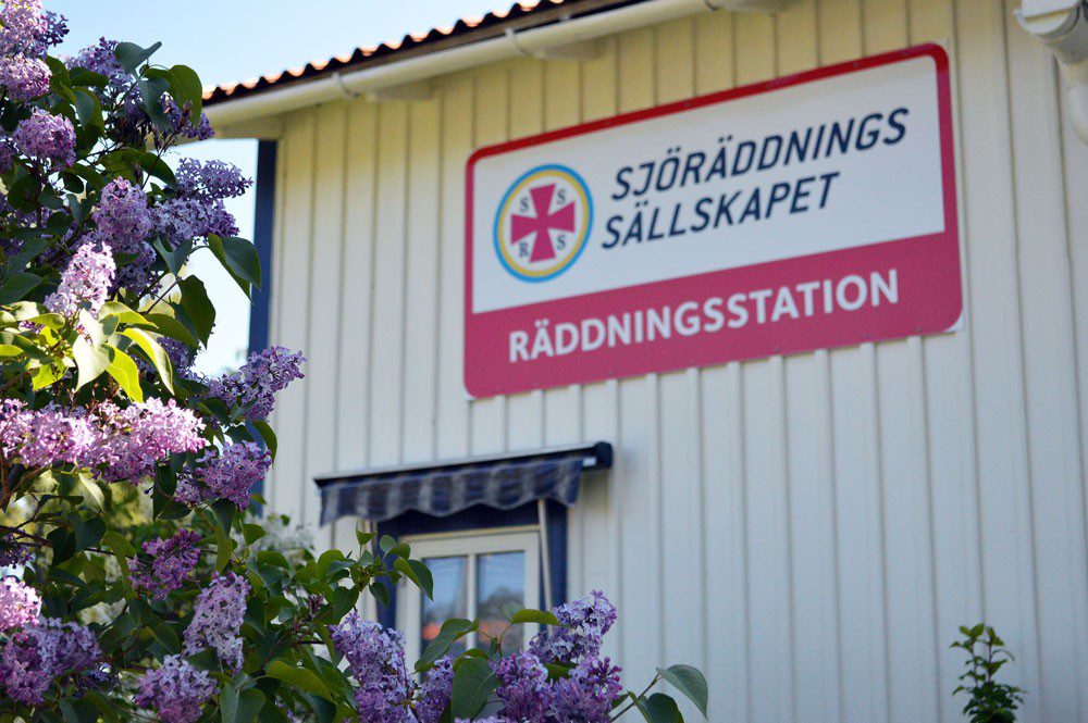 Villa med skylt " Sjöräddningssällskapet Räddningsstation" och syren i förgrunden