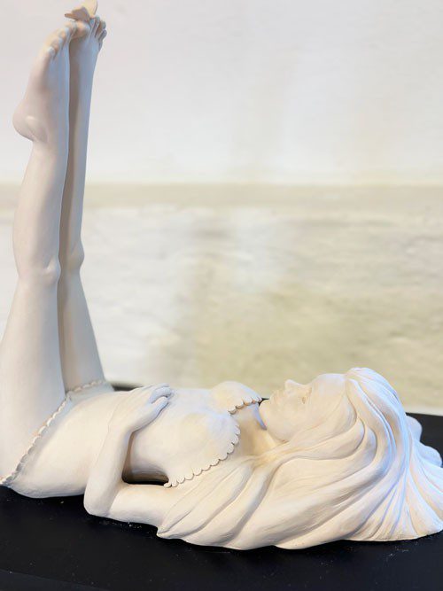 Skulptur föreställande en kvinna som ligger på rygg med fötterna uppe i luften