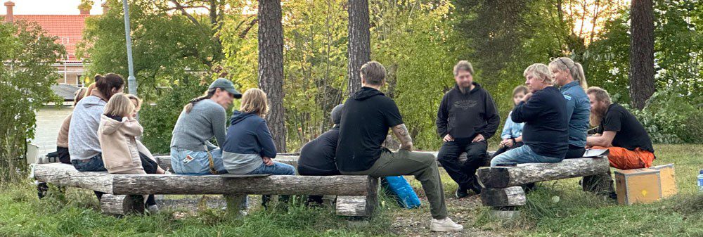 En grupp människor sitter i en cirkel av stockar