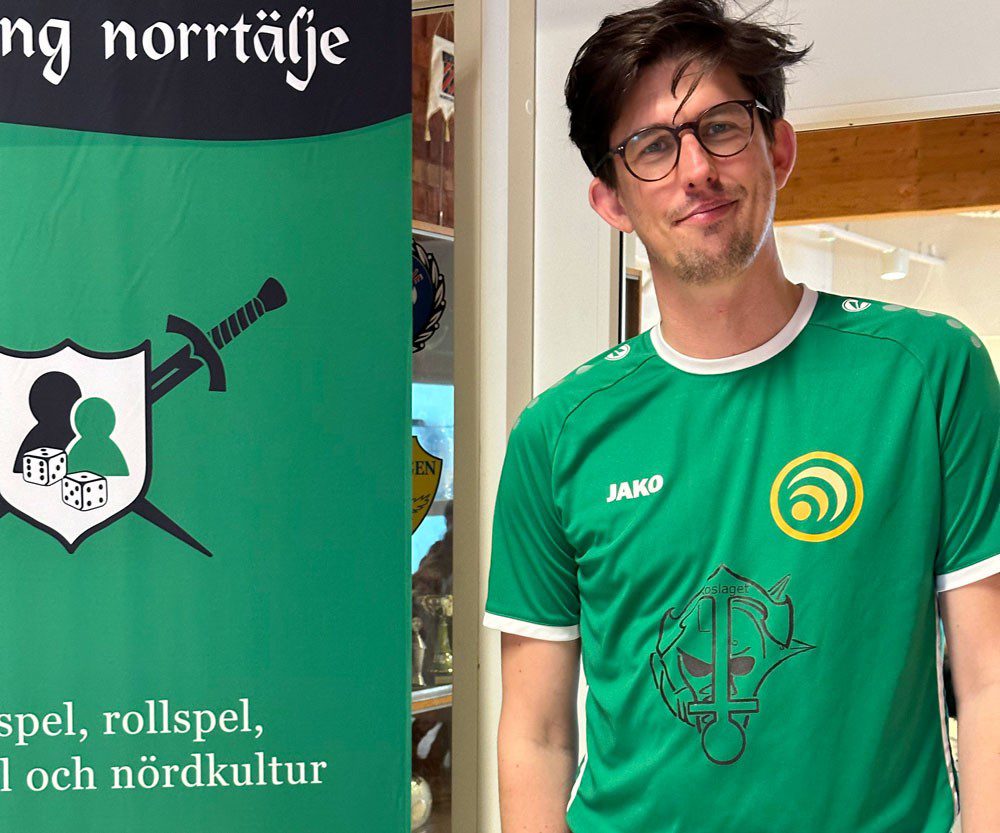 En man i en grön tröja står bredvid en grön roll-up banner
