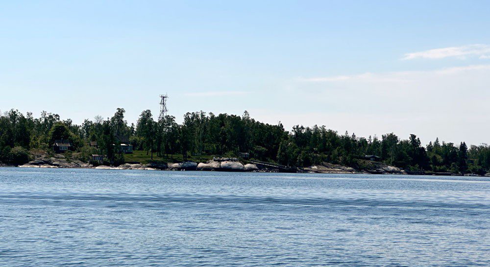 Sjö i förgrunden med träd och ett torn på andra sidan vattnet