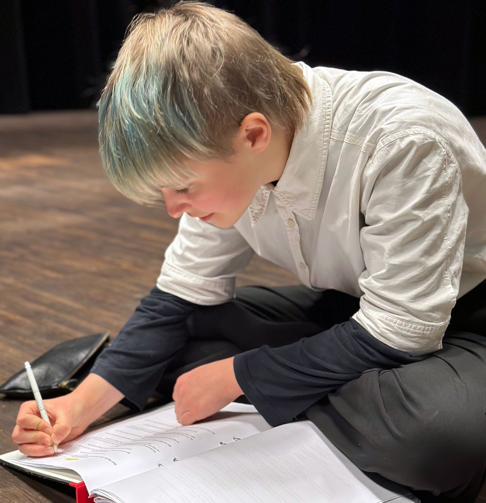 En ung kvinna sitter på golvet och skriver i en pärm