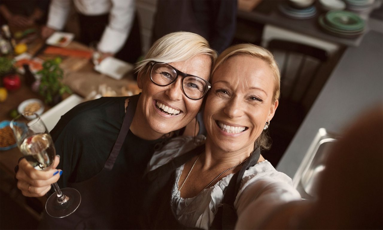 Kvinnor tar en selfie och har håller ett glas i handen.