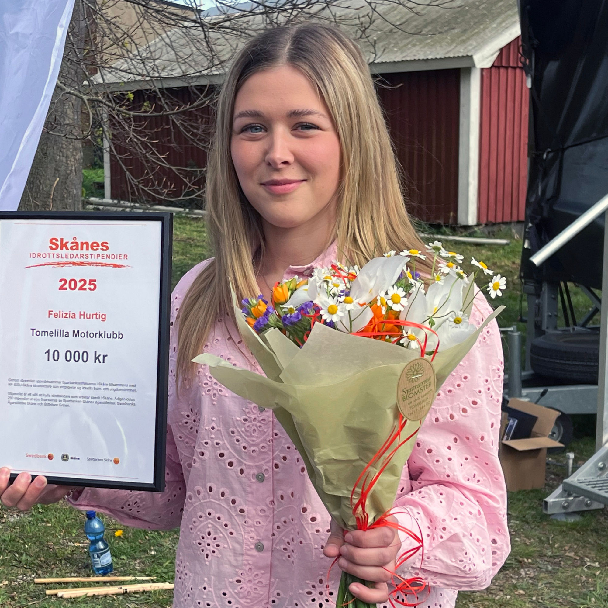 Felizia Hurtig  håller upp sitt Skånes Idrottsledarstipendium.