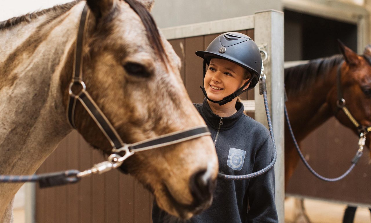 En häst och tjej inne i ett stall