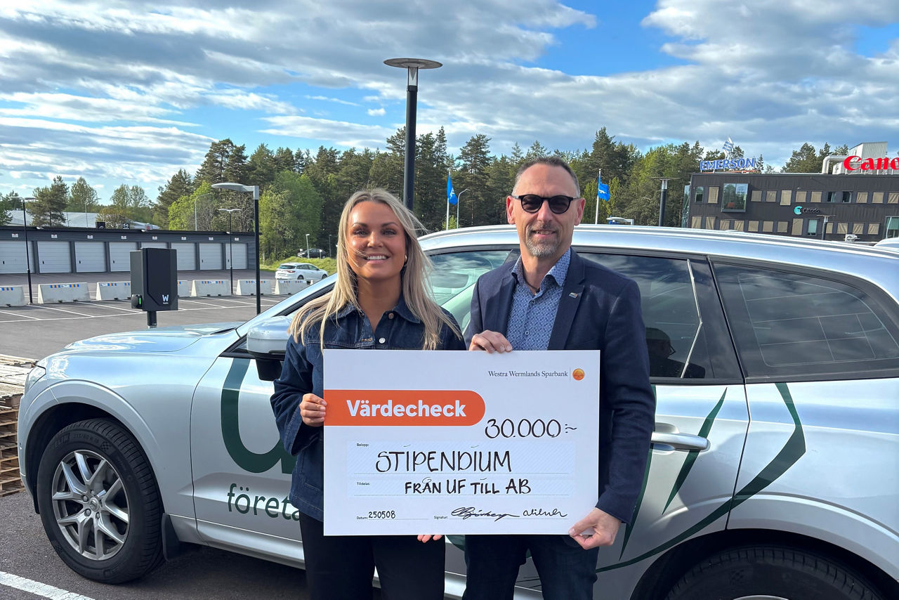 en man och en kvinna står framför en bil och håller upp en check
