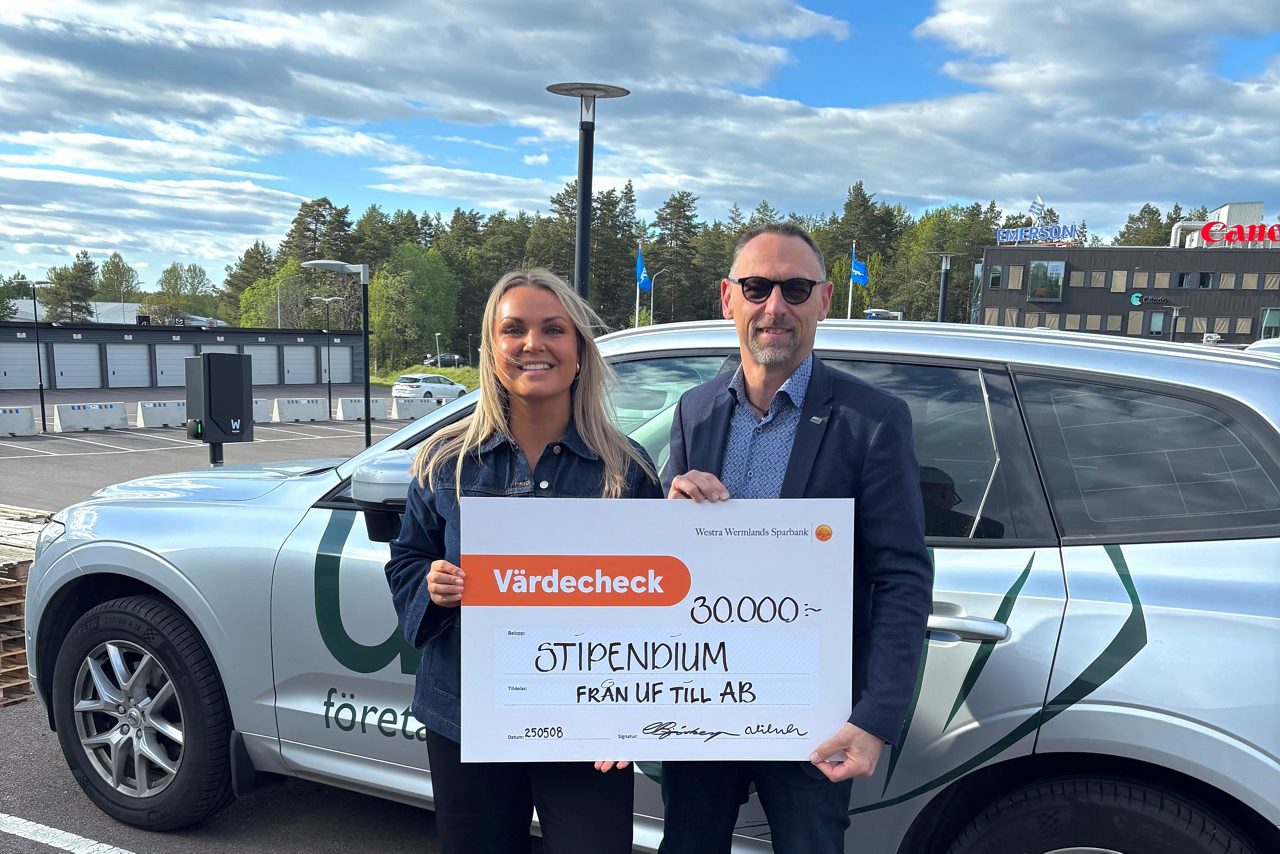 en man och en kvinna står framför en bil och håller upp en check
