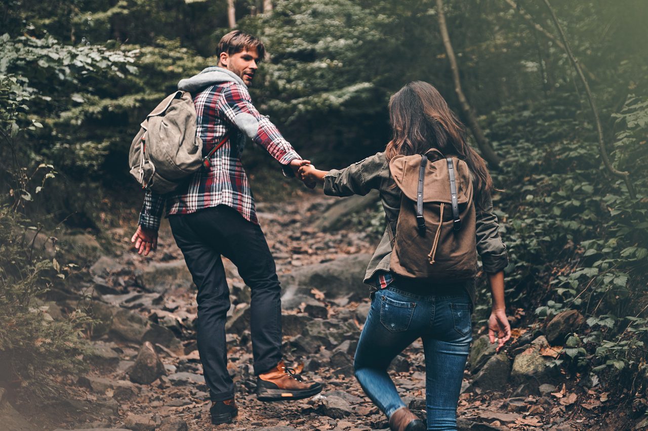 Par håller hand på promenad i skogen