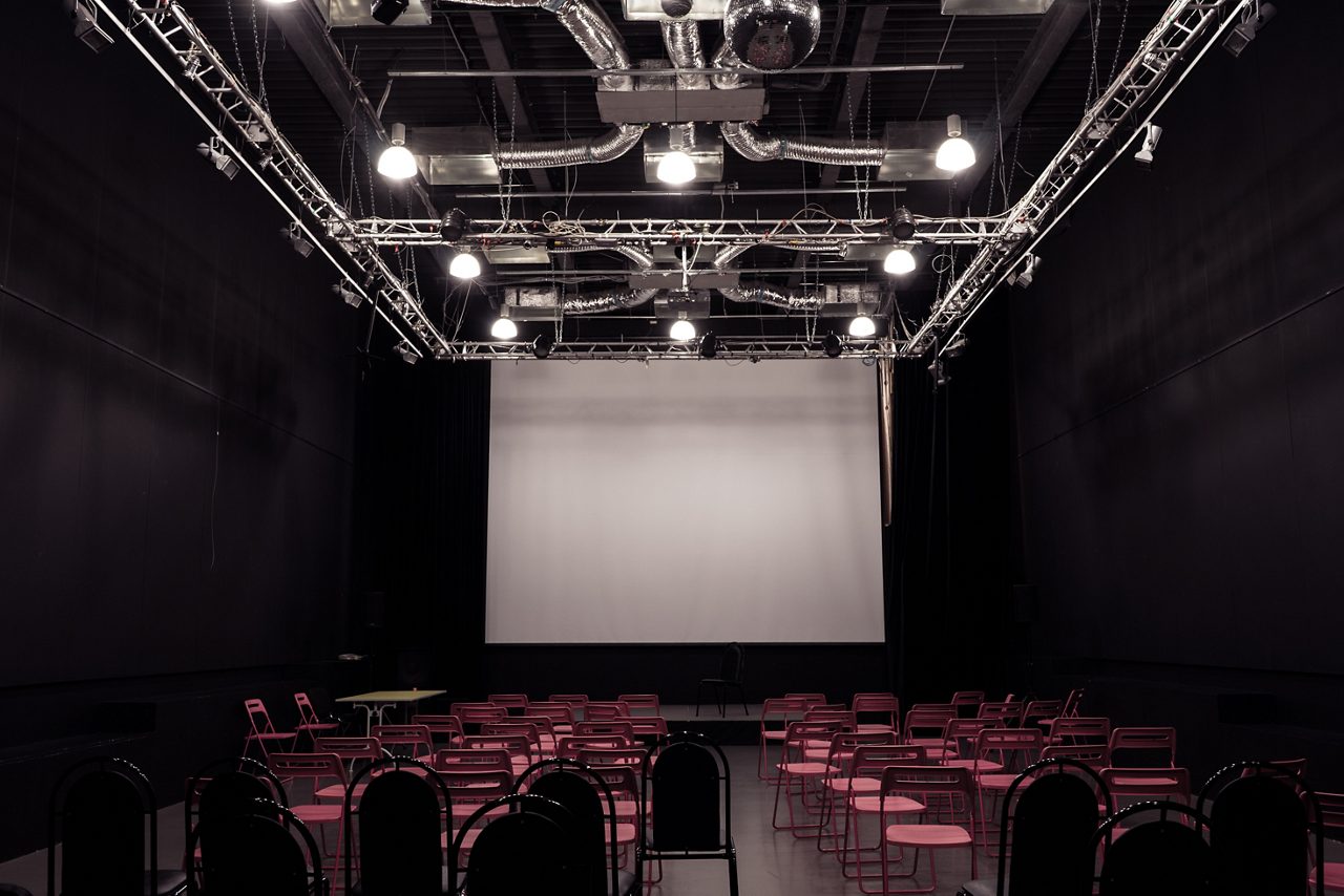 Stor konferens med biosittning av flera röda stolar och färgad belysning