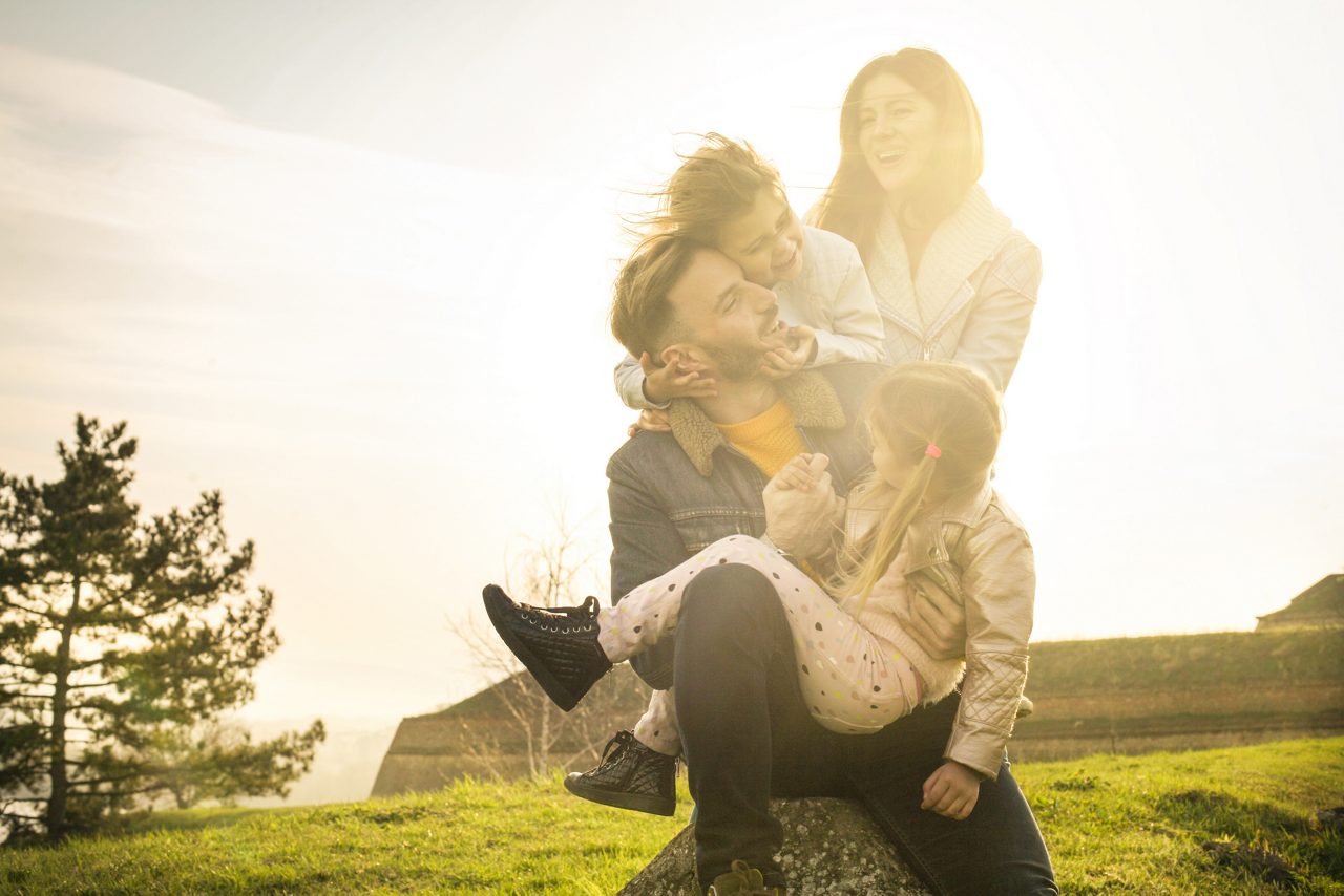 Glad familj skojar utomhus i motljus