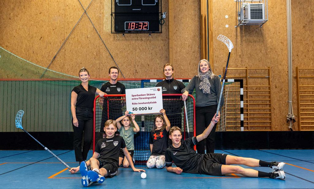 Innebandyspelare från Röke Innebandyklubb står runt ett mål och håller upp en check.