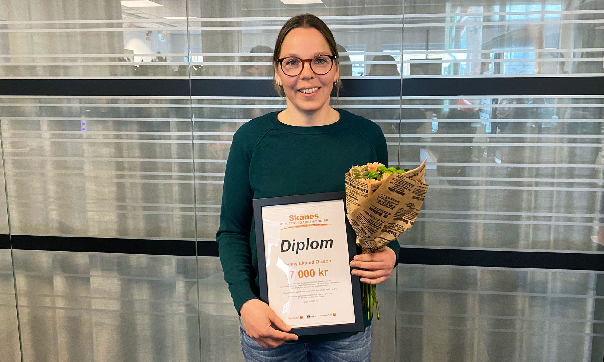 Jenny Eklund Olsson håller upp sitt idrottsledarstipendium. 
