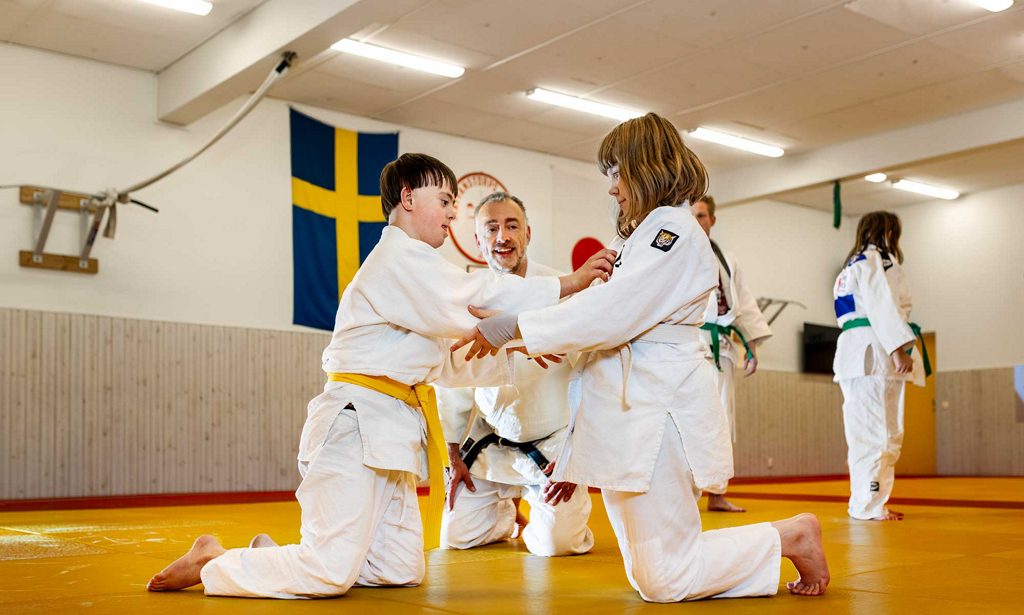 Barn i en judohall gör judoövningar.
