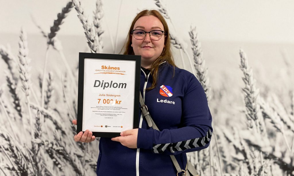 Julia Södergren håller upp sitt idrottsledarstipendium i händerna.