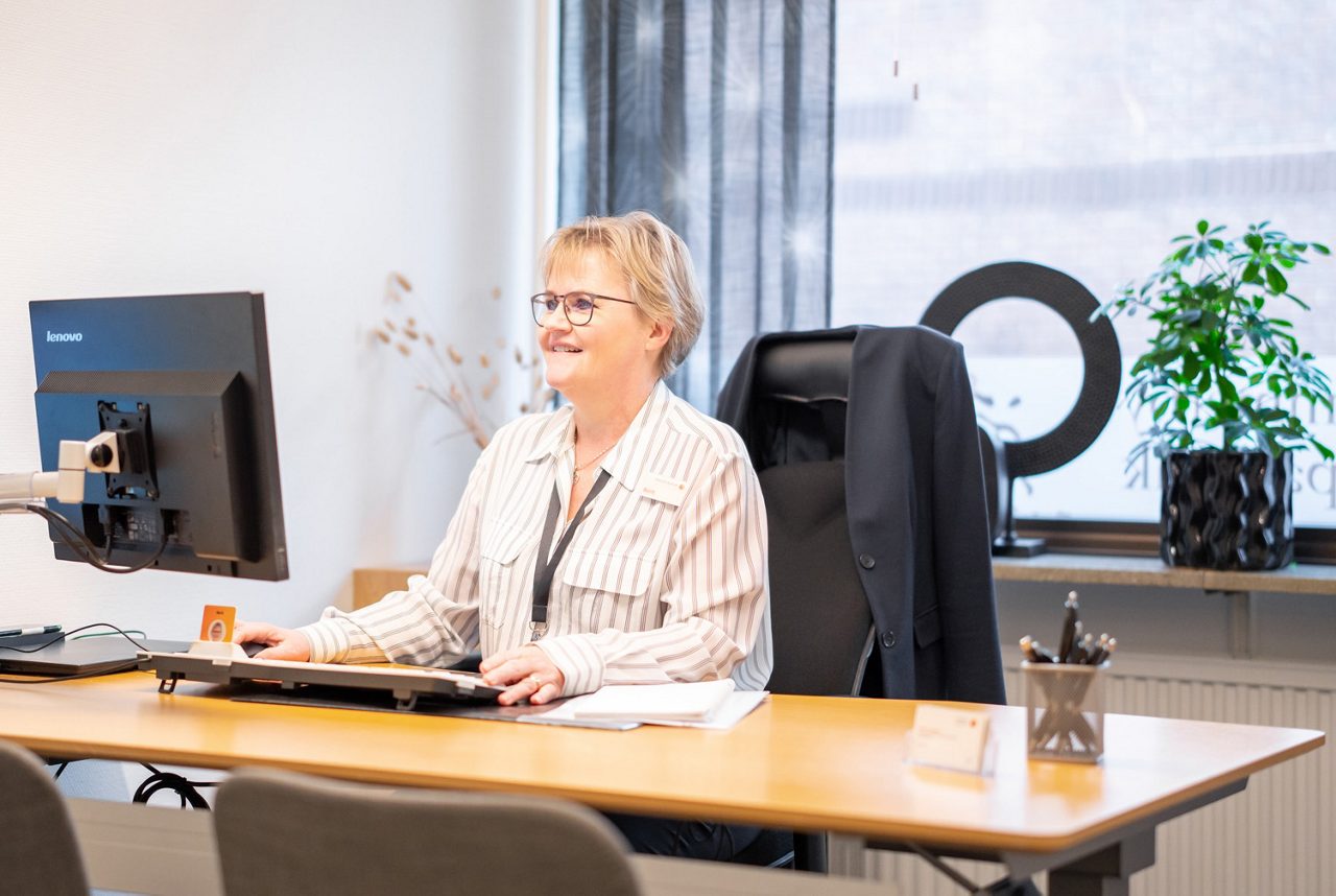 Leende kvinna bakom ett skrivbord i ett kontor