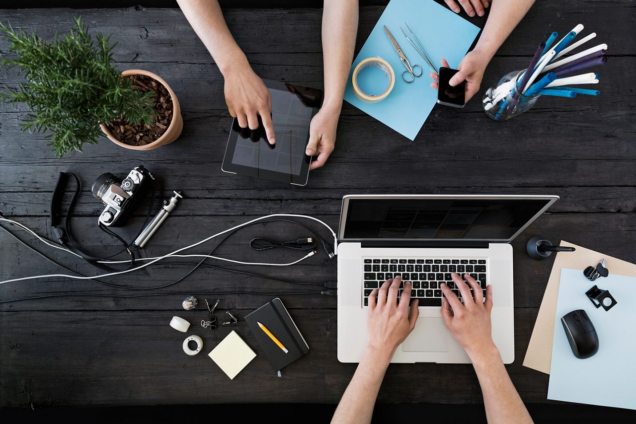 Digital devices and paper and pencils on a table.