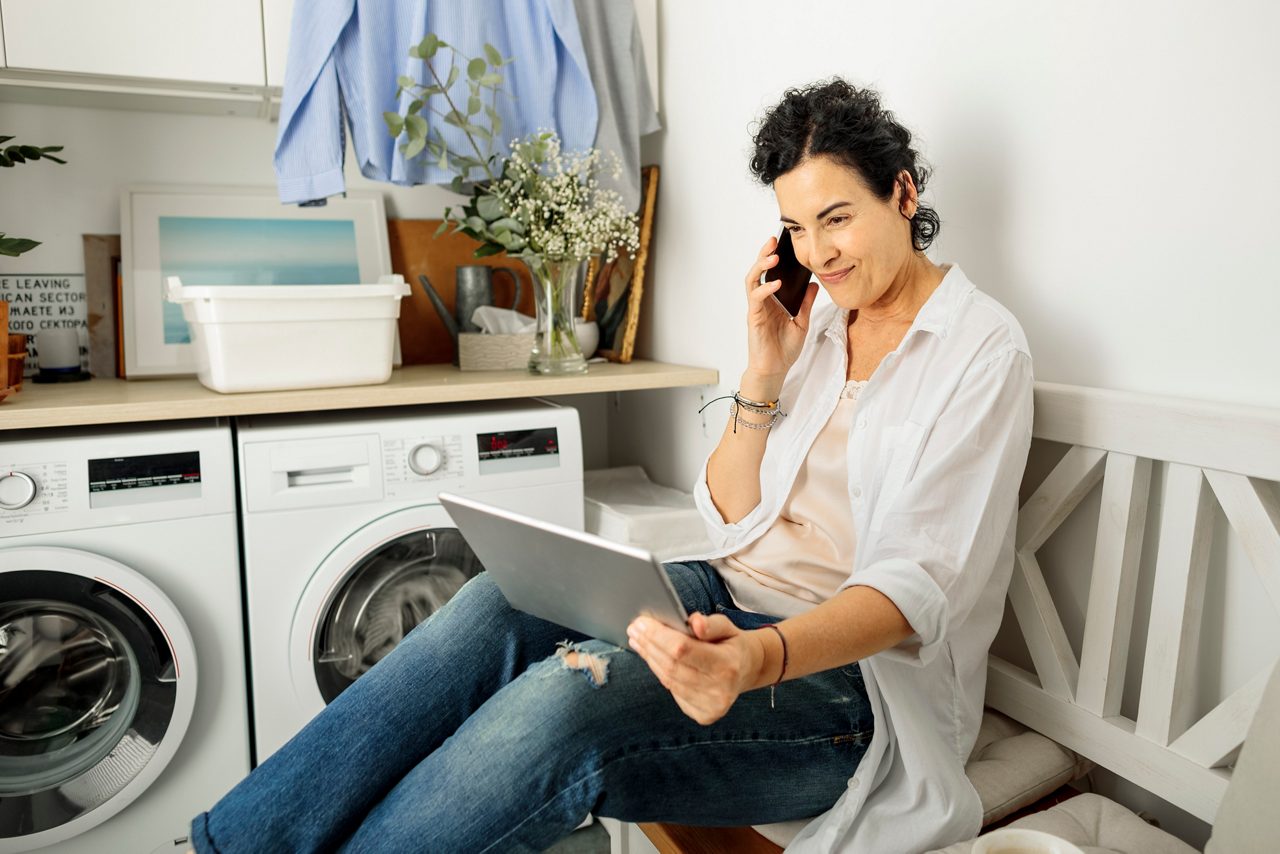 Kvinna i pratar i telefon i tvättstugan