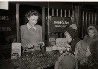 A bank cashier helps customers at a savings bank branch, old black and white photo