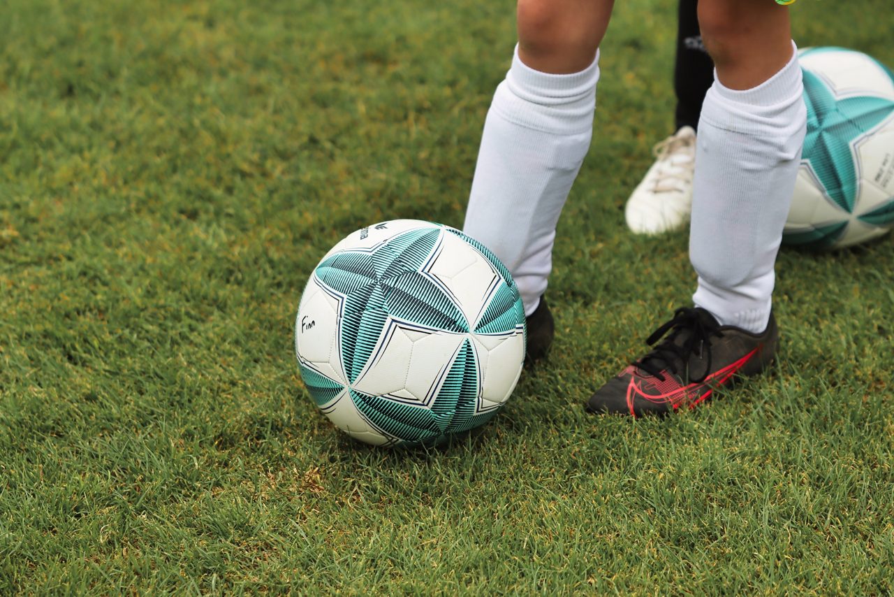 Ung fotbollsspelare med en fotboll på en gräsplan