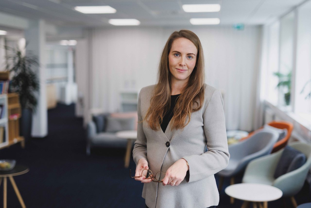 En kvinna som står i ett rum och håller glasögon i händerna.