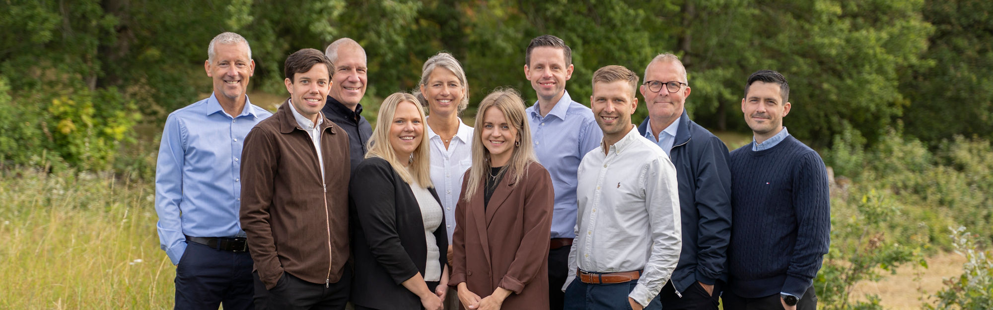 All personal som arbetar med företagskunder på Tidaholms Sparbank står tillsammans med en skog i bakgrunden.
