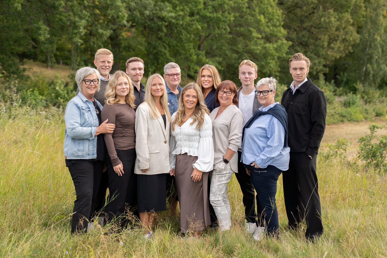 All personal som arbetar i kassa/kundtjänst på Tidaholms Sparbank står tillsammans med en äng i bakgrunden.