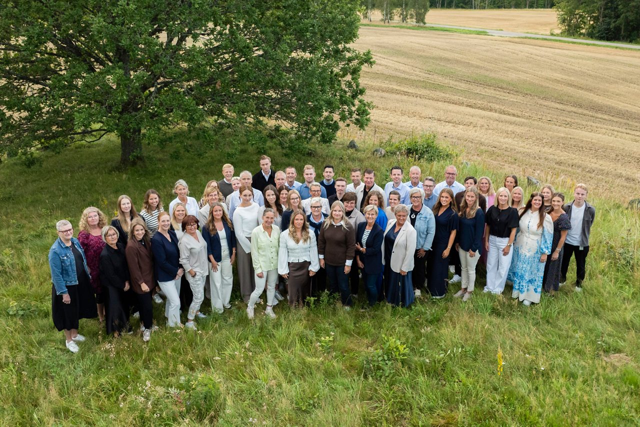 All personal på Tidaholms Sparbank står tillsammans med en stor ek i bakgrunden.