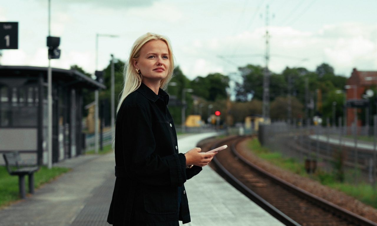 tjej som står på perrongen och väntar på sitt tåg.