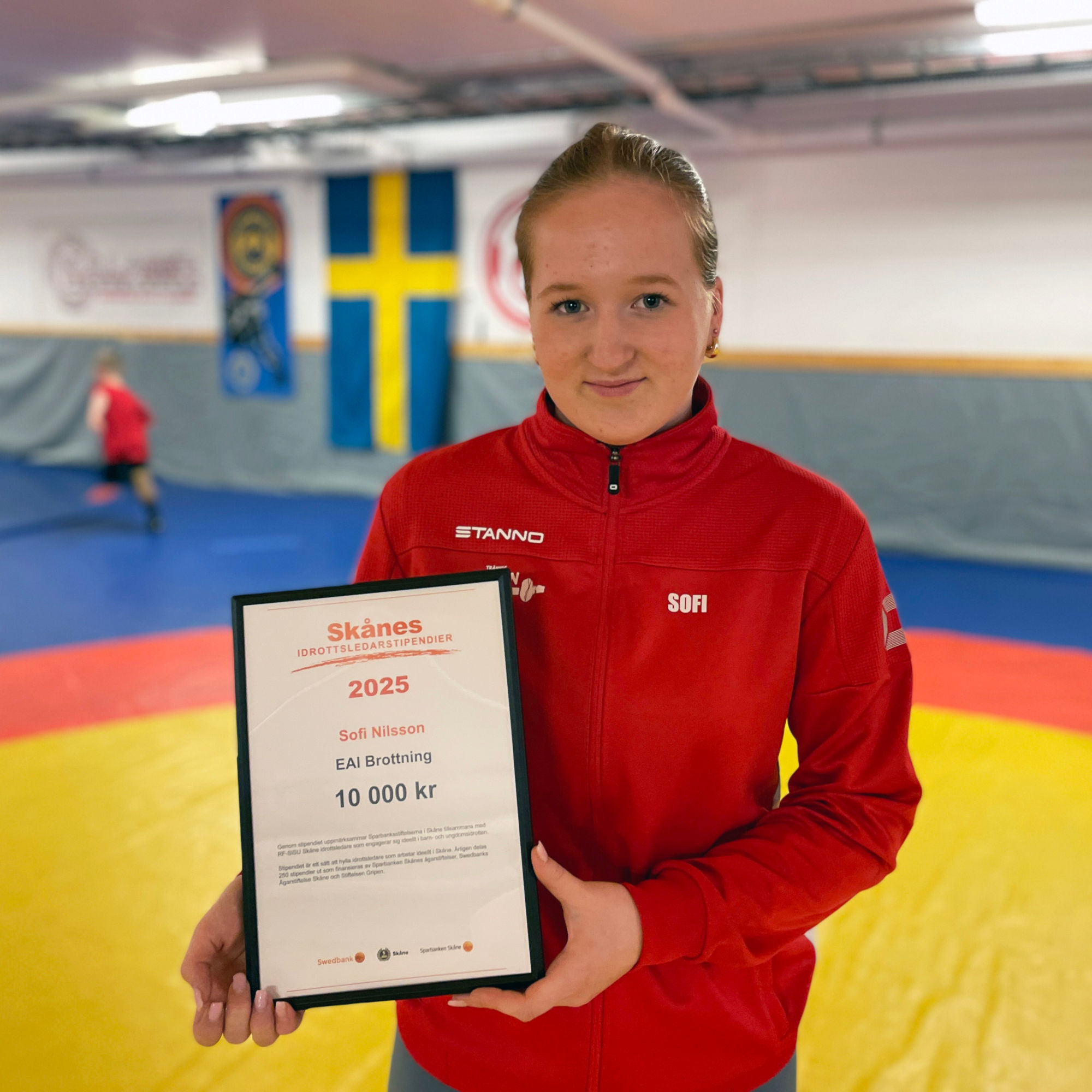 Sofi Nilsson håller upp sitt Skånes Idrottsledarstipendium.