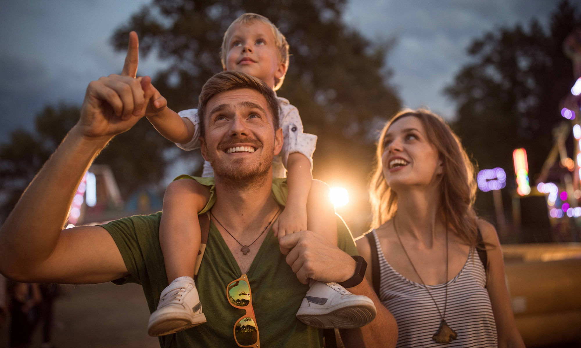 Man and woman standing with a child on the shoulder and looking up..
