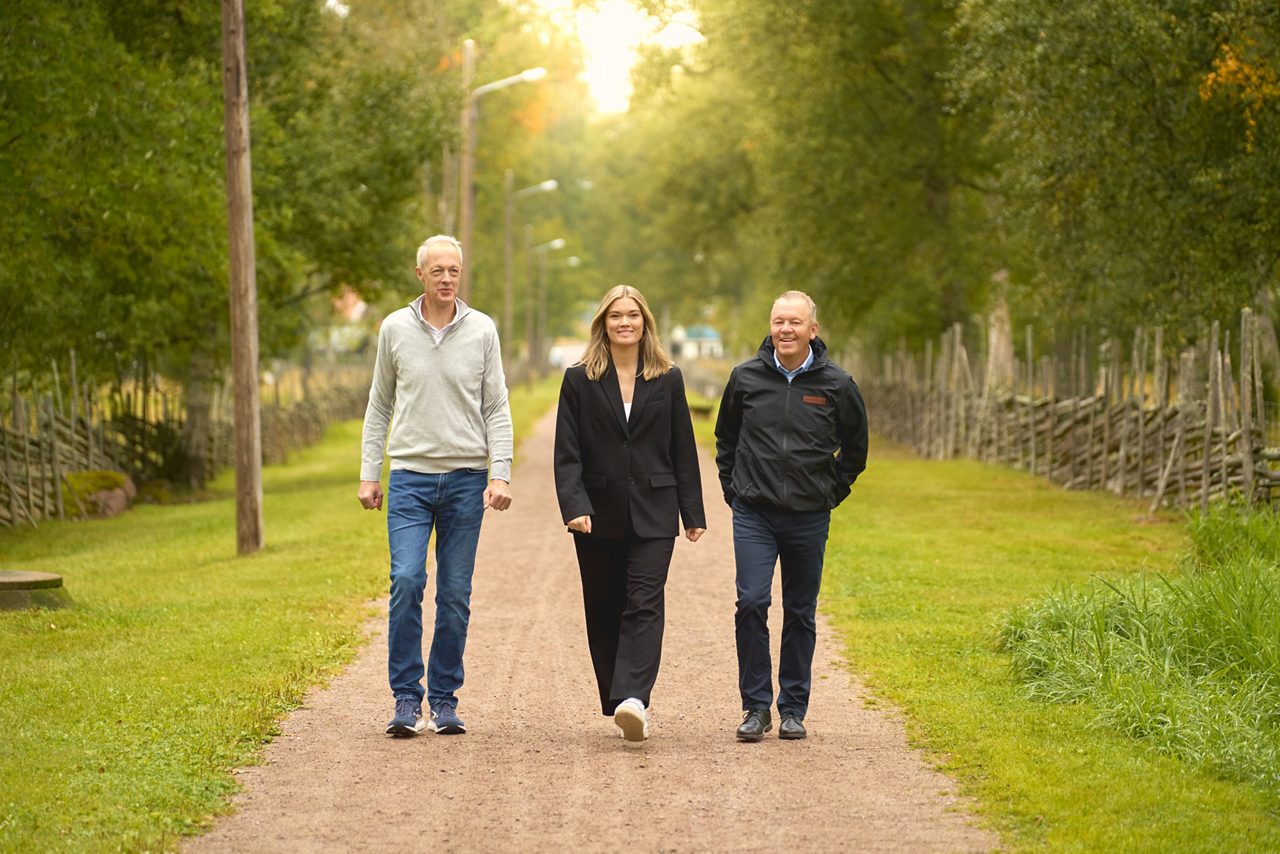 Tre personer går mot oss på en grusväg