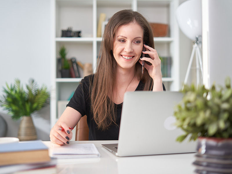 Woman working from home taking a call and making notes