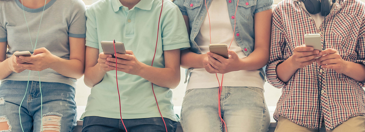 Kinder stehen in einer Gruppe und hören Musik auf ihrem Smartphone