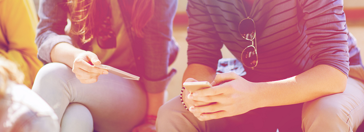 Teenager sitzen auf einer Bank mit einem Smartphone in der Hand