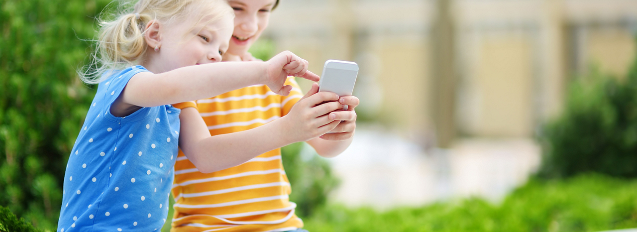 Zwei Kinder spielen zusammen an einem Smartphone