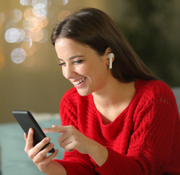 Junge Frau, die lächend auf ihr Smartphone schaut