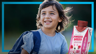 Une jeune fille avec un sac à dos, une boisson protéinée dans une brique alimentaire aseptique Tetra Prisma 