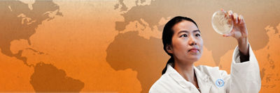 Expert in lab coat looking at petri dish