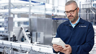 Homem com óculos inspecionando embalagem na fábrica.