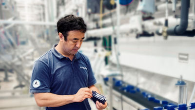 Worker using a laptop to inspect equipment in an industrial processing facility.