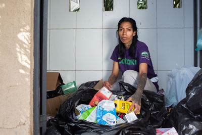 Femme assise à l&#39;extérieur avec un sac poubelle rempli d&#39;emballages carton