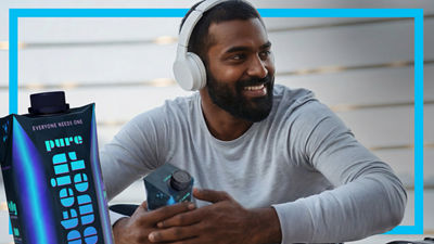 Young man with headphones and mobile phone, protein drink in Tetra Prisma Aseptic carton