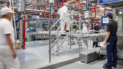 Employees beside a Tetra Brik Aseptic packaging machine in a production hall