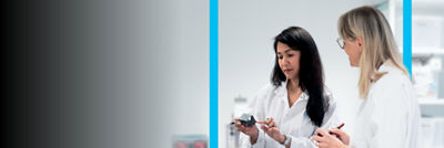 Due scienziati in camici da laboratorio che esaminano un dispositivo e discutono i loro risultati in un ambiente di laboratorio.