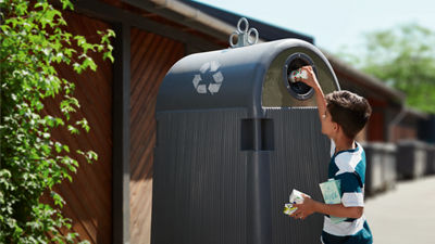 kid recycling carton in bin