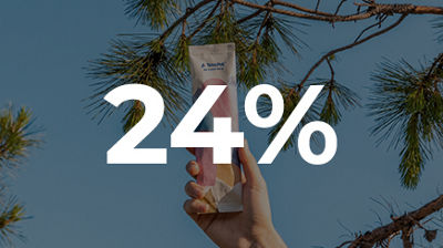 A hand holds a wrapped ice cream beneath pine branches against a blue sky, with 24% displayed across the image.