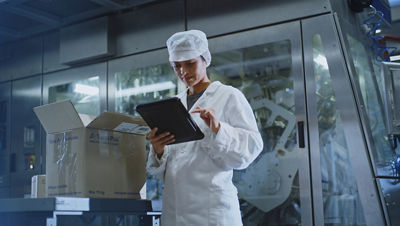 一位身着白色外套的女士正在技术中心工作，埋头专心查看平板电脑。