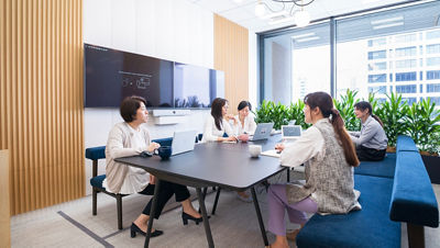 Colleagues collaborate around a desk in a modern office filled with natural light and plants.